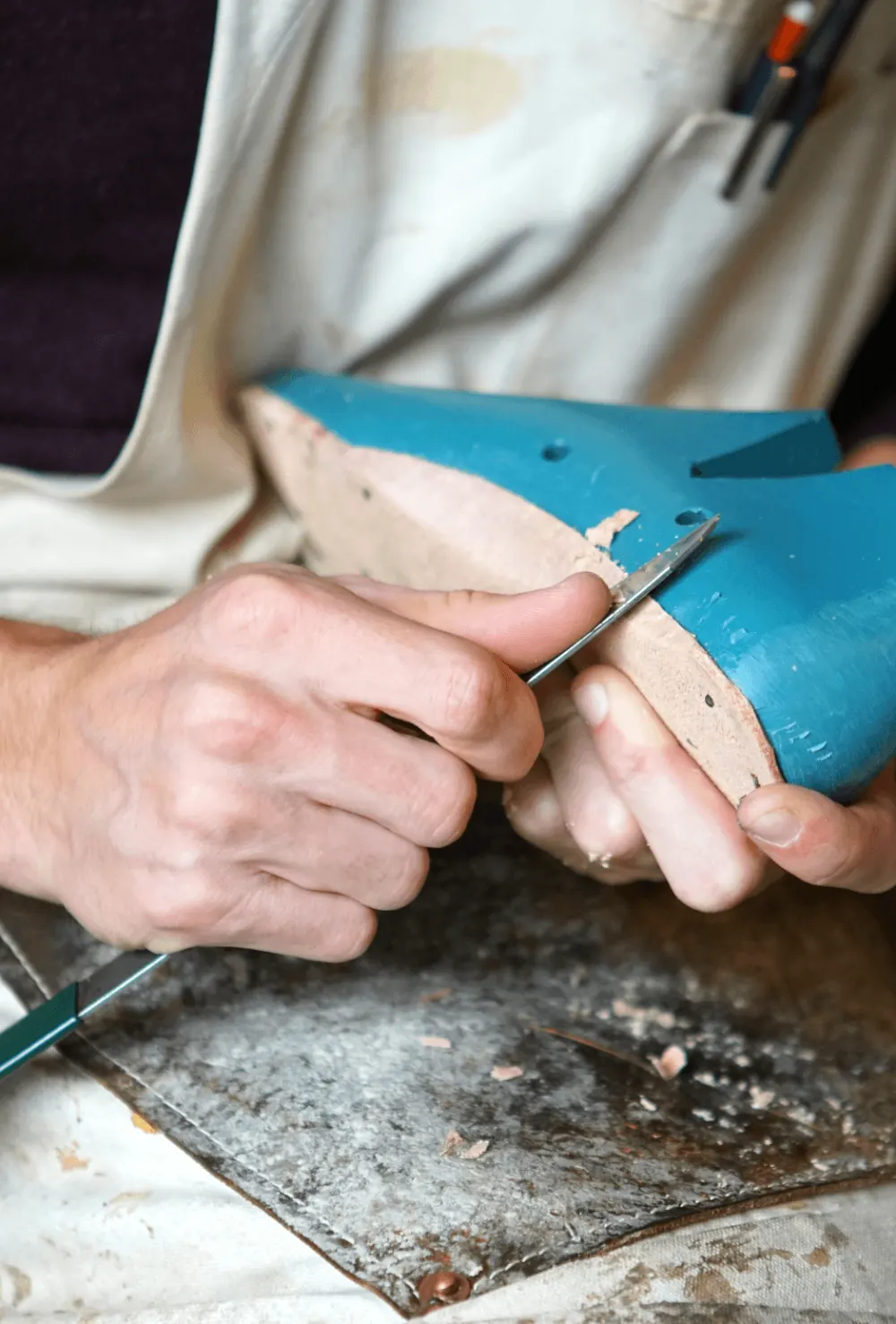 Un calzolaio lavora a mano la tomaia di una scarpa